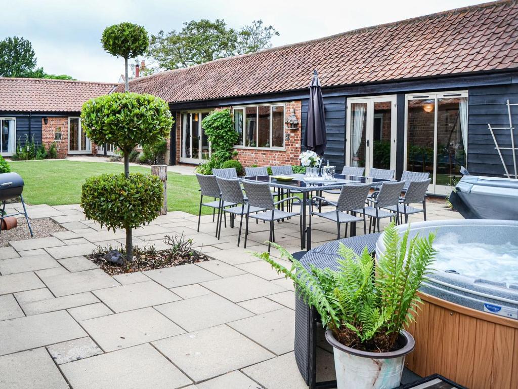a patio with a table and chairs and a hot tub at Lodge Farm Barn in South Walsham