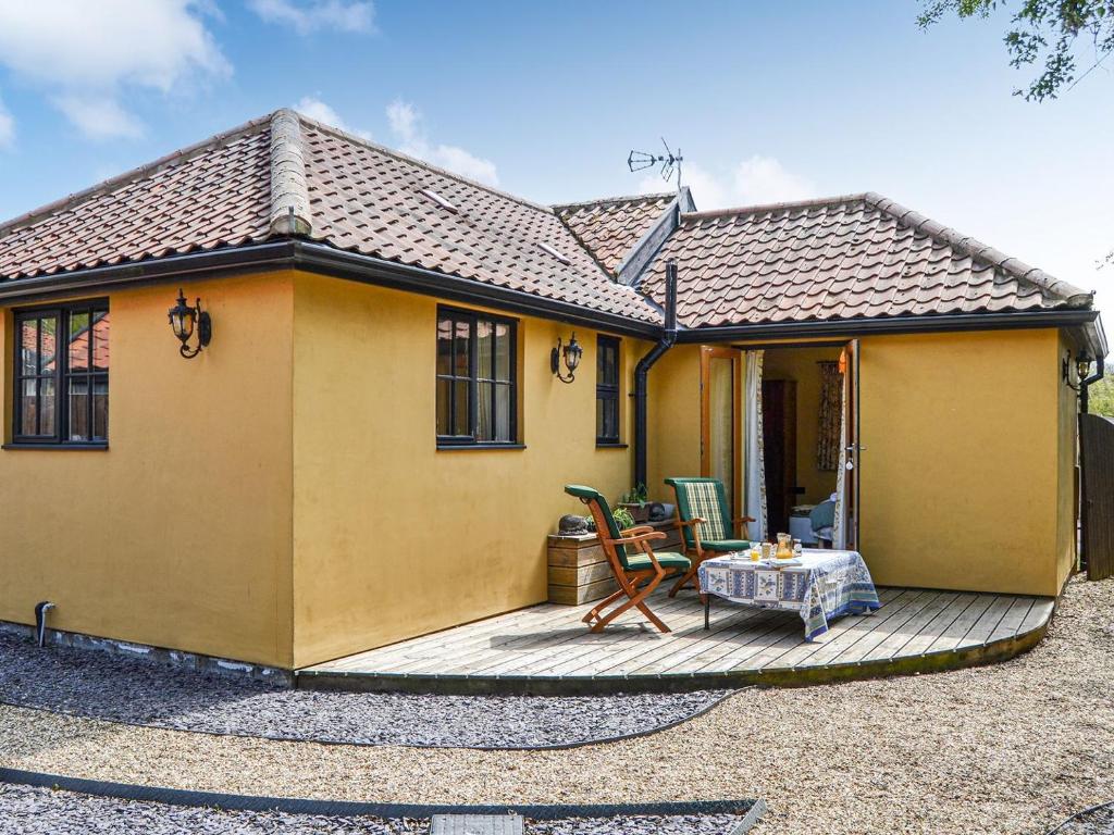 a yellow house with a table on a deck at Bradcar Farm Cottage in Snetterton