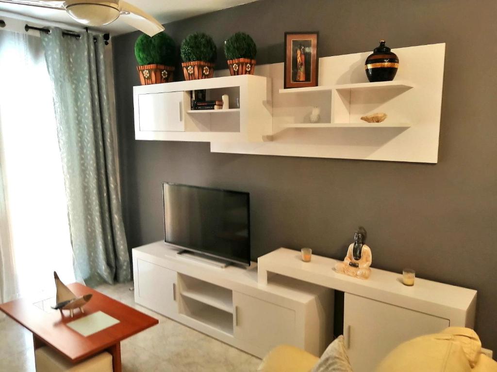 sala de estar con estanterías blancas y TV de pantalla plana en Precioso apartamento de lujo en Torredembarra