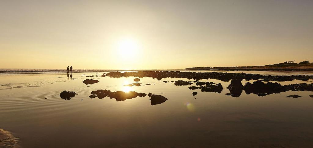 a sunset on a beach with rocks in the water at Nature et decouverte a Brem sur Mer in Brem-sur-Mer