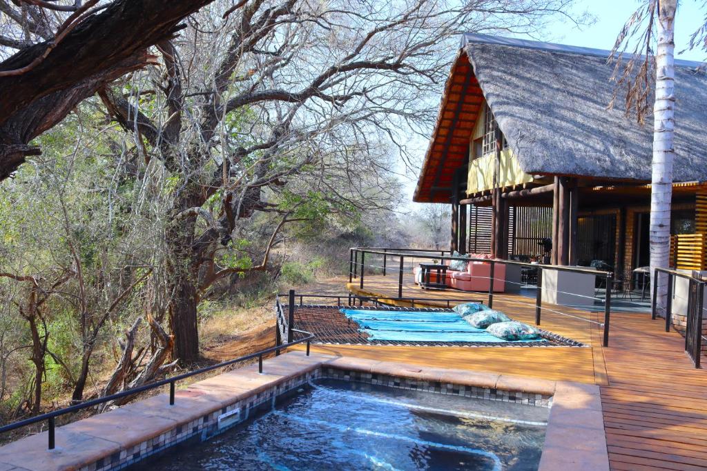 a house with a swimming pool next to a wooden deck at Bundox Villas in Hoedspruit