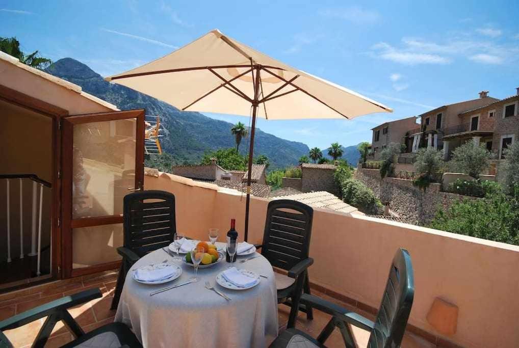 een tafel met een parasol op een balkon bij Casa Fornalutx with Air Conditioning and a roof terrace with great views in Fornalutx