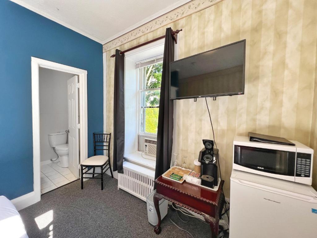 a room with a television on a wall with a window at Inn at the Falls in Bracebridge