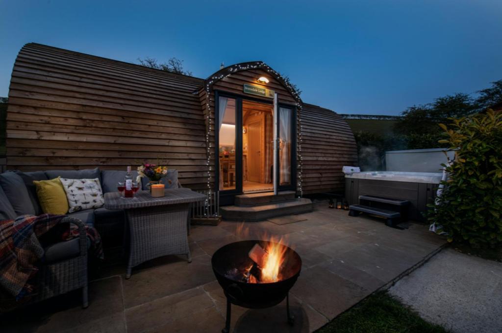 a backyard patio with a fire pit and a tub at Humble Bee Farm Glamping in Folkton
