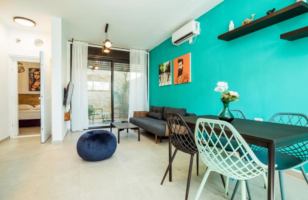 un soggiorno con parete blu, tavolo e sedie di הרצל בוטיק מבית דומוס - Herzl Boutique Apartments by Domus a Beer Sheva