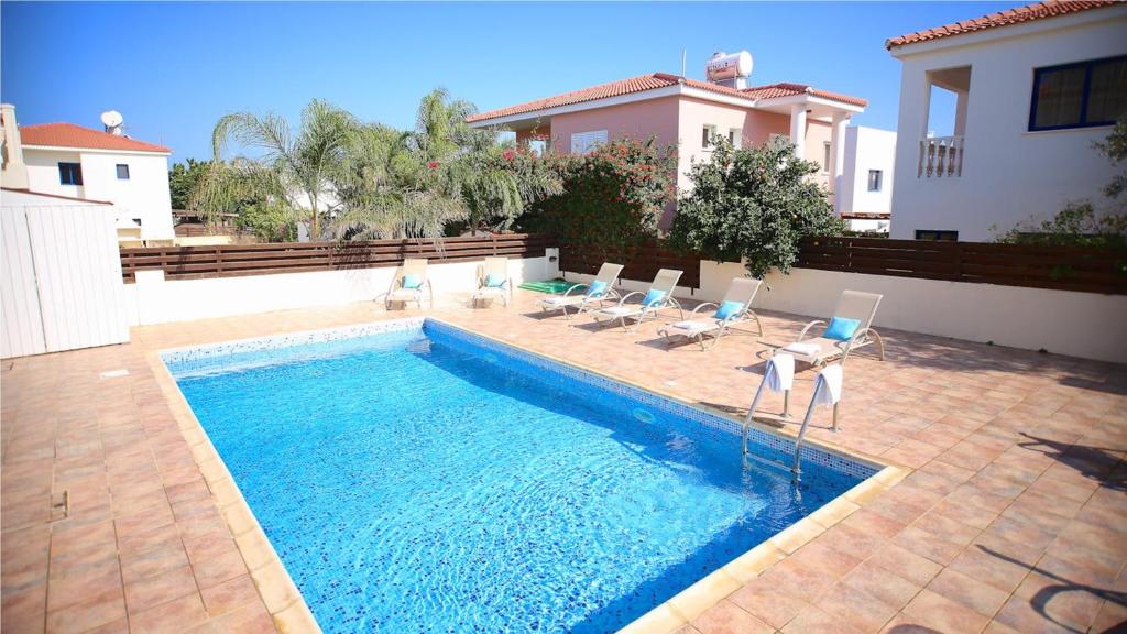 a swimming pool with chairs and a house at Kapparis Holiday Villa 114 in Protaras