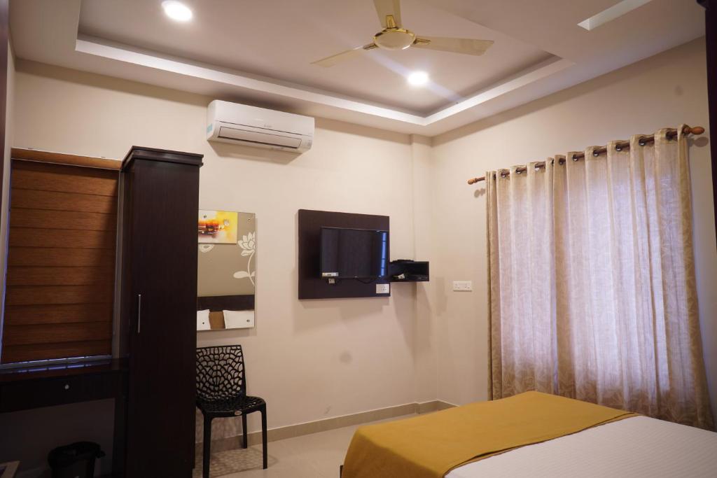 Metro Residency في كوتشي: غرفة نوم مع سرير وتلفزيون على الحائط