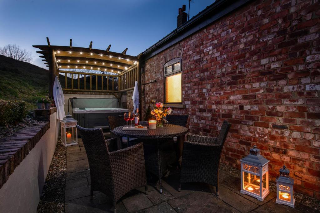 a patio with a table and chairs and a brick wall at Humble Bee Farm in Scarborough