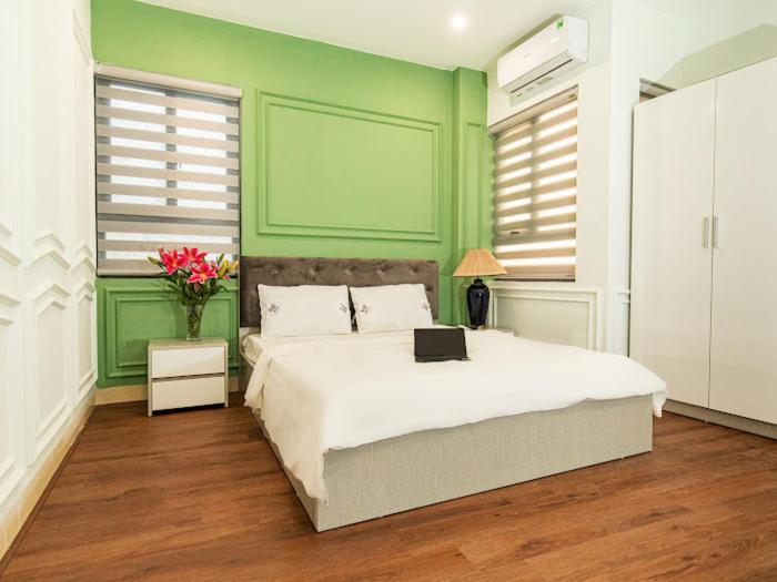 1 dormitorio verde con 1 cama con ordenador portátil en Madelise Max Hotel, en Hanói