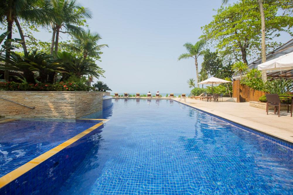 uma grande piscina azul com o oceano ao fundo em Juquehy Praia Hotel em Juquei