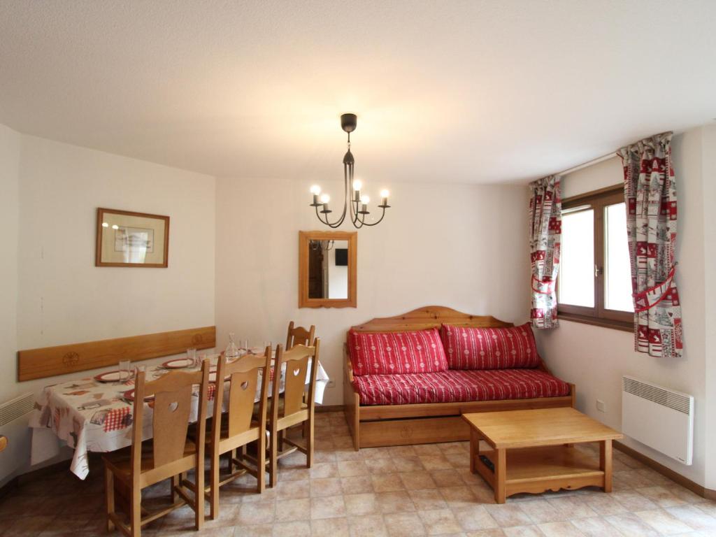 a dining room with a table and a red couch at Appartement Lanslevillard, 3 pièces, 6 personnes - FR-1-508-46 in Lanslevillard