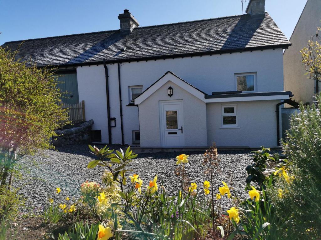 a white house with yellow flowers in front of it at Hillside Farm Cottage in Grange Over Sands