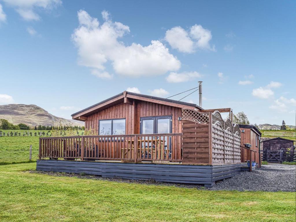 a wooden cabin with a large deck in a field at Islabank Lodge in Auchterarder