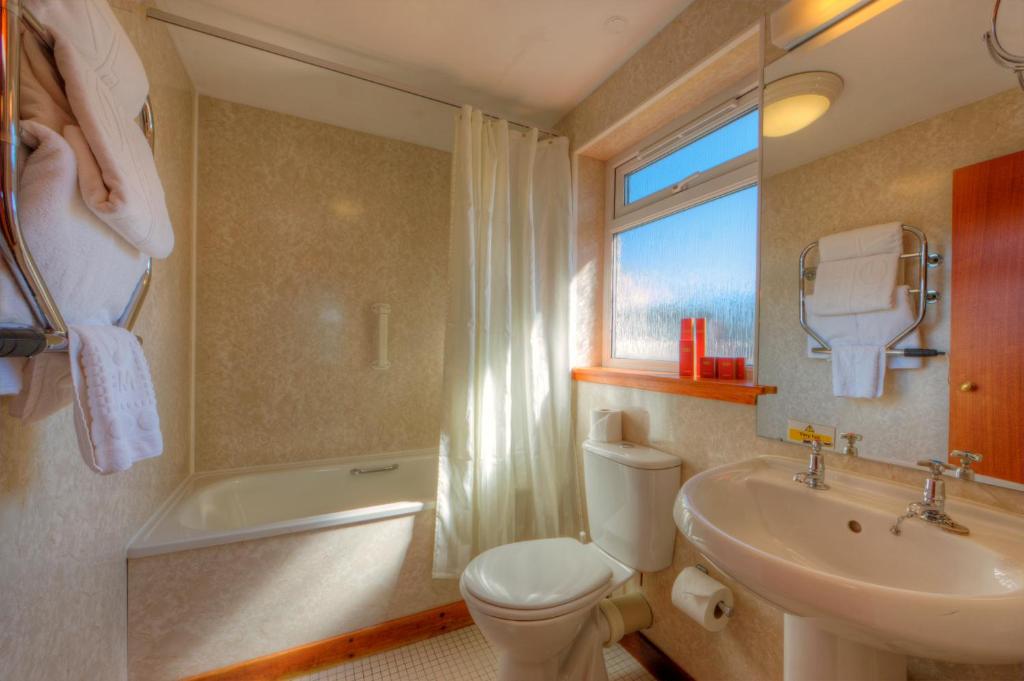 a bathroom with a toilet and a sink and a tub at Muthu Alexandra Hotel in Oban
