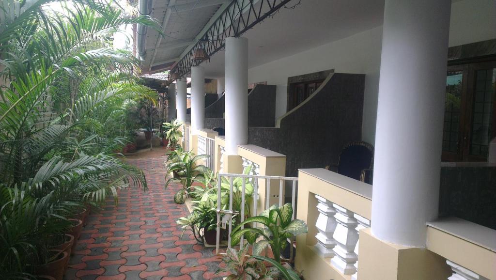 a corridor of a building with palm trees and plants at Alba Rooms Palolem Rosebuds in Palolem