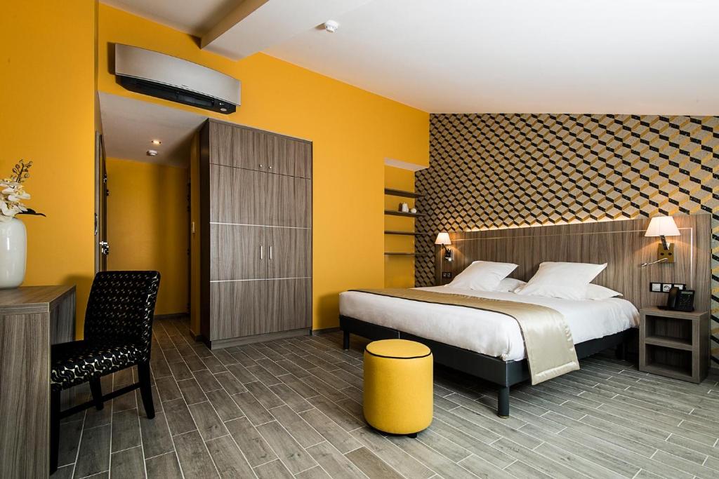 een hotelkamer met een bed en een stoel bij Unique Hôtel & Spa in Saint-Raphaël