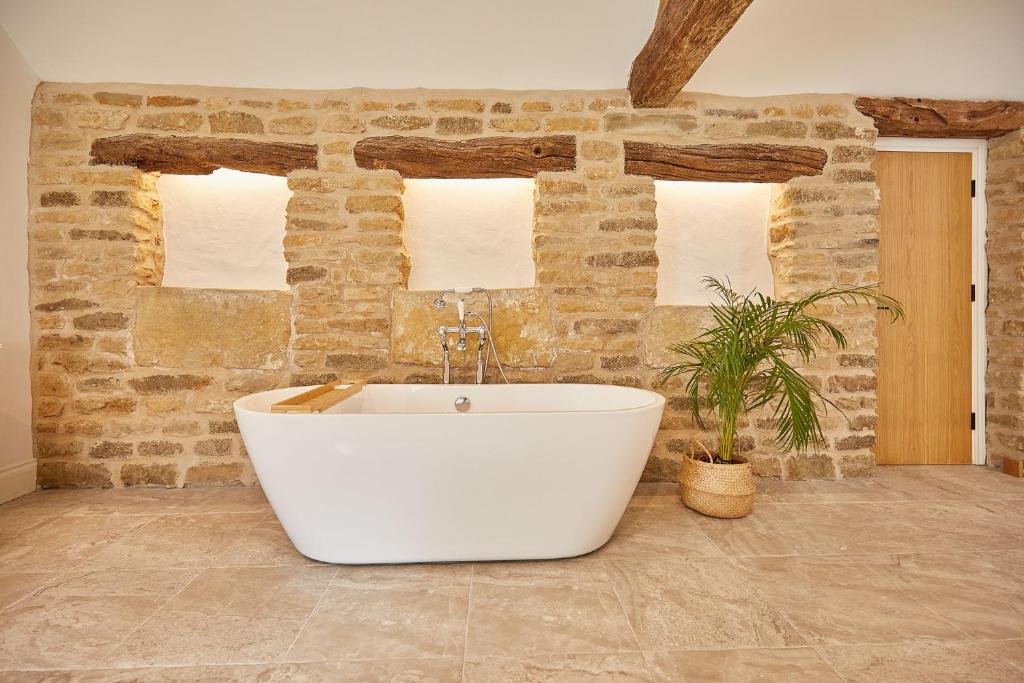 a bath tub in a bathroom with a stone wall at The Irishman's Cottage in Yedingham