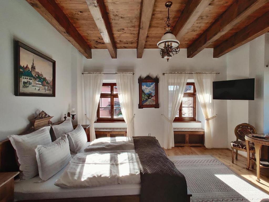 1 dormitorio con 1 cama en una habitación con ventanas en La Teo Pensiune si Pivnita en Sighişoara