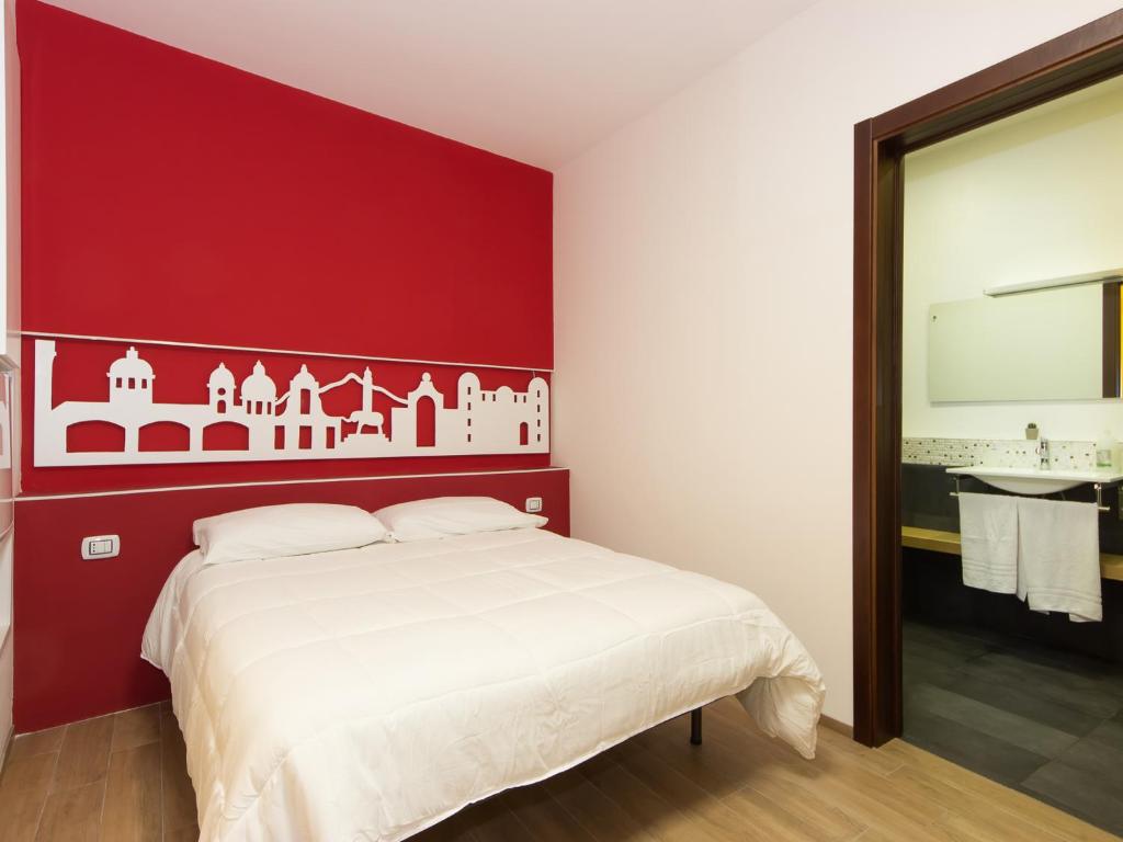 a bedroom with a red wall and a white bed at Central Rooms Il Re in Catania