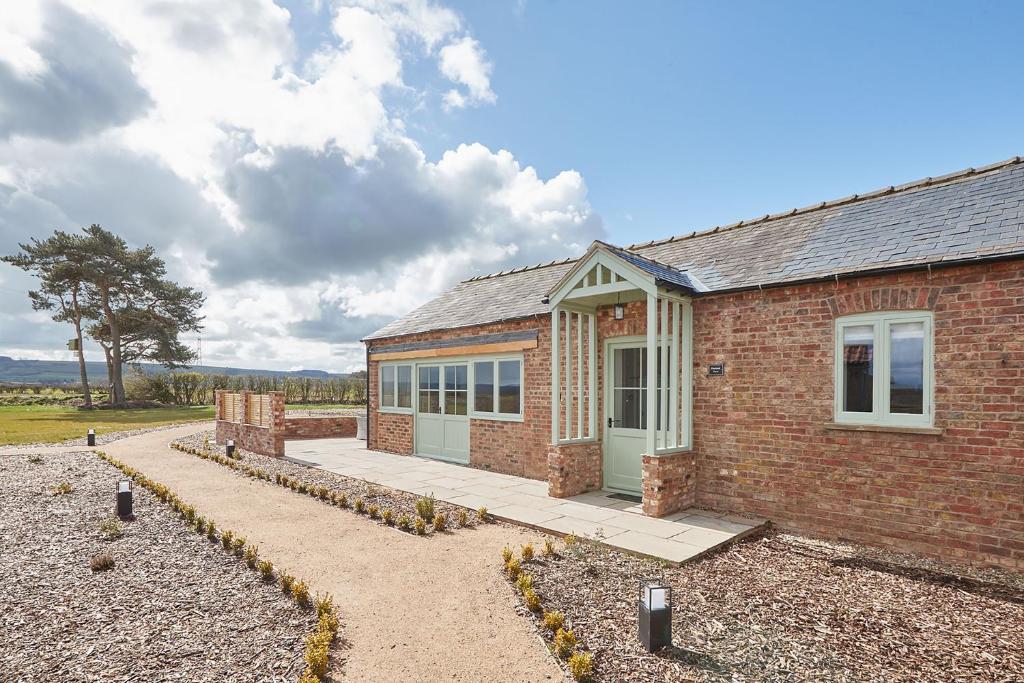 a brick house with a patio in front of it at Orchard View Cottage in Yedingham