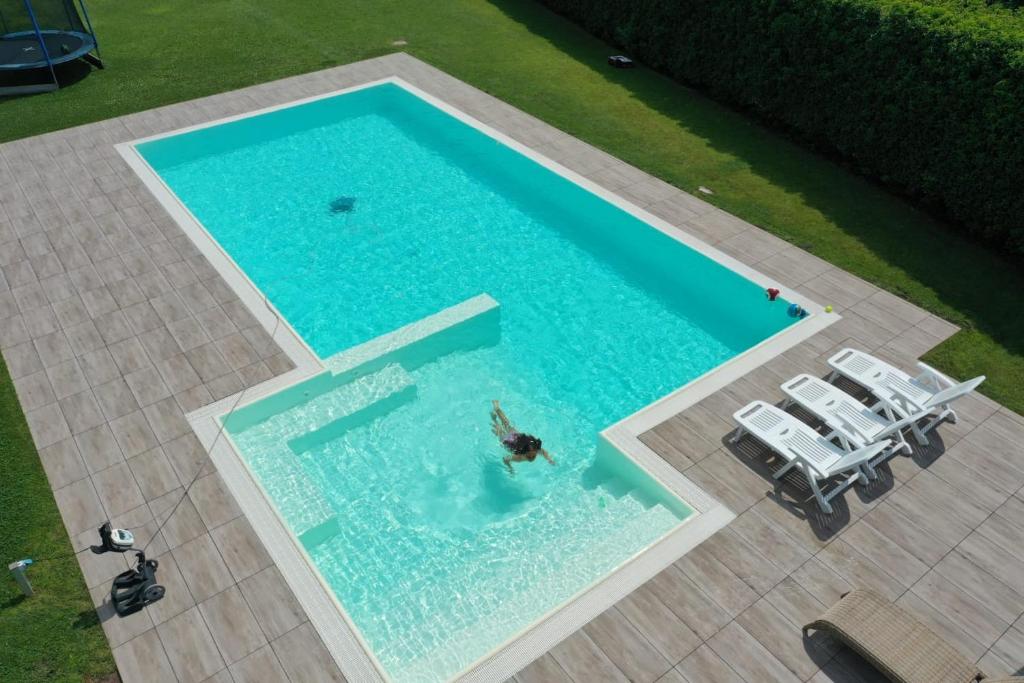 eine Person, die in einem großen Pool mit Stühlen schwimmt in der Unterkunft App in Villa con Piscina - 45 min Venezia - Zona Unesco in San Pietro di Feletto