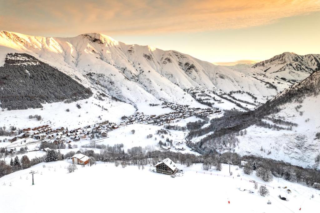 une station de ski dans la neige avec des montagnes en arrière-plan dans l'établissement Les Cèdres - Hôtel - Restaurants - Spa, à Saint-Sorlin-dʼArves