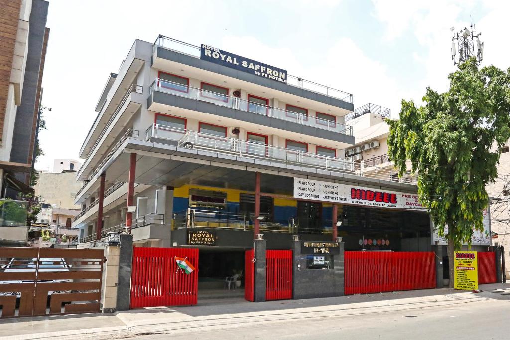 un edificio con una valla roja delante de él en Hotel Royal Saffron - Kirti Nagar en Nueva Delhi