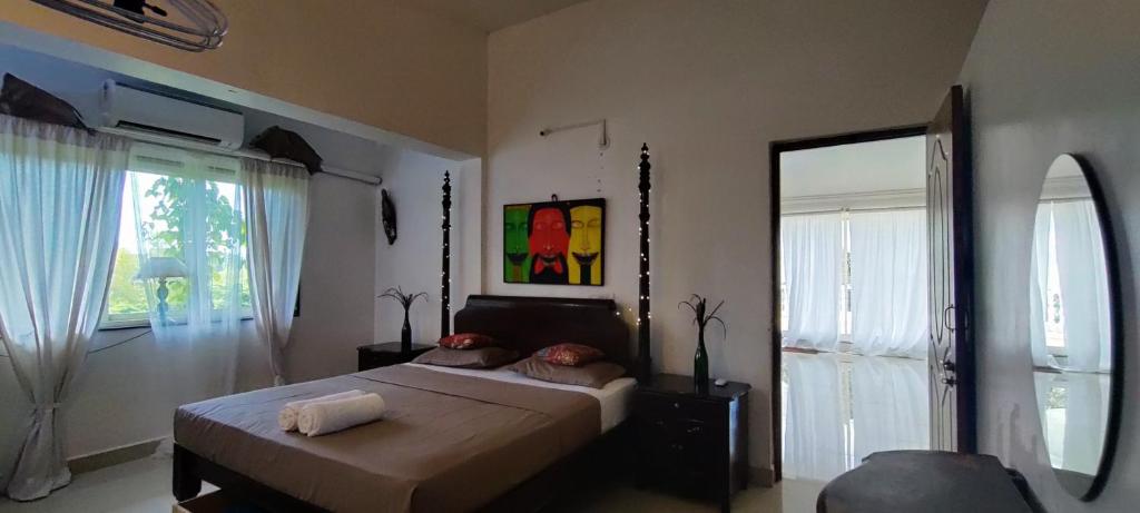 a bedroom with a bed and a large window at J-House, spacious apartments with balconies, Thalassa 1min away in Siolim