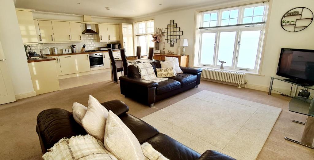 a living room with two couches and a kitchen at Shore Thing Beachfront Apartment Ramsgate - Sleeps 4 in Ramsgate
