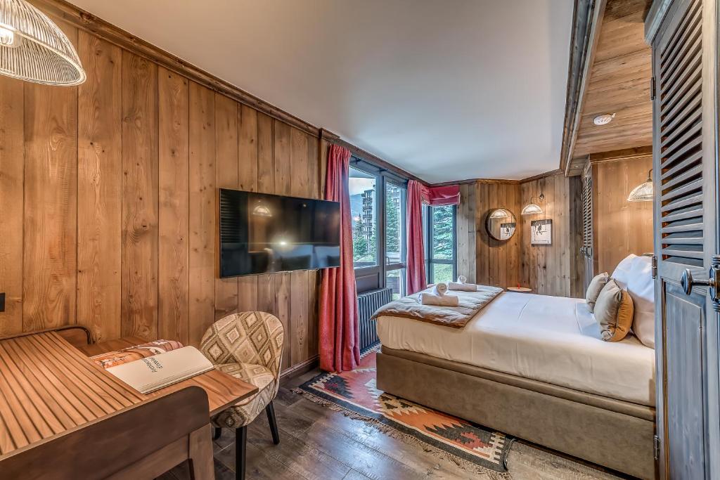 a bedroom with a bed and a desk and a table at Hotel & Spa Le Val d'Isère in Val-d'Isère