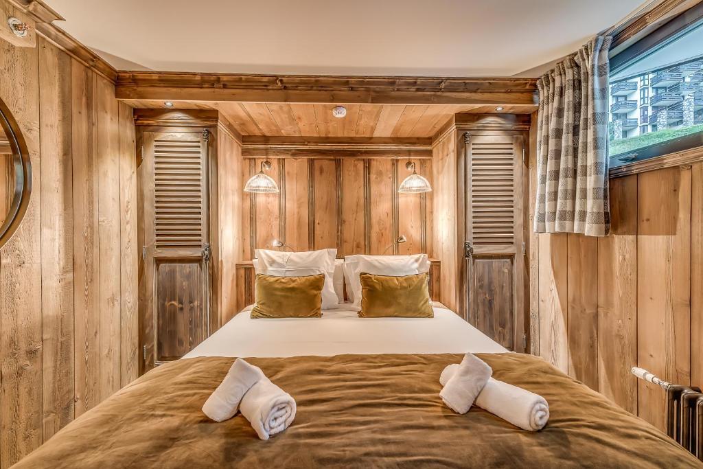 a bedroom with a large bed in a wooden wall at HOTEL LE VAL D&#39;ISERE in Val-d&#39;Isère