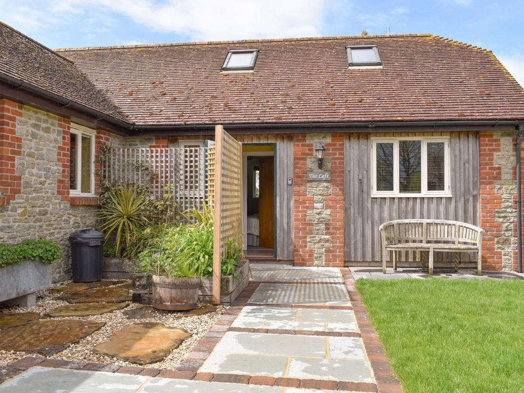 a brick house with a bench in the yard at The Loft in Holwell