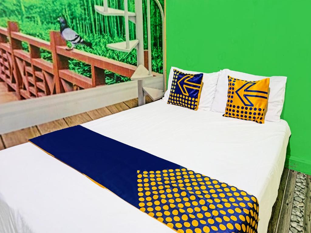um quarto com uma cama com almofadas amarelas e azuis em OYO 91697 Nyaman Homestay Syariah em Pare