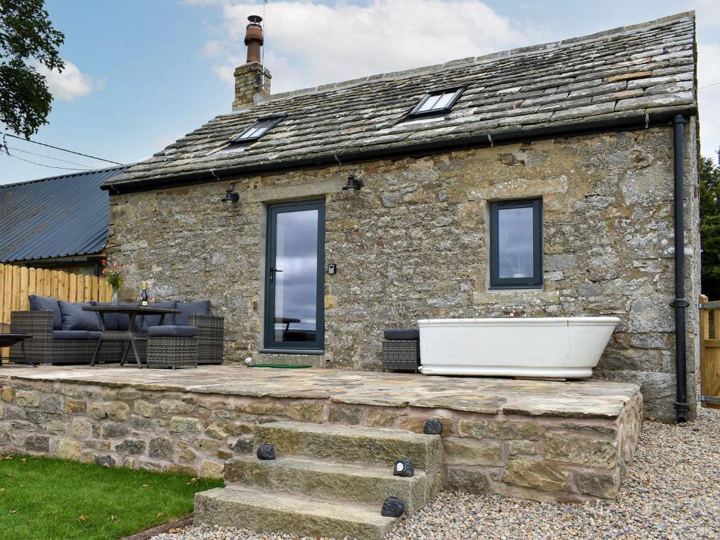 a stone cottage with a bath tub in front of it at Harsondale Bothy in Langley