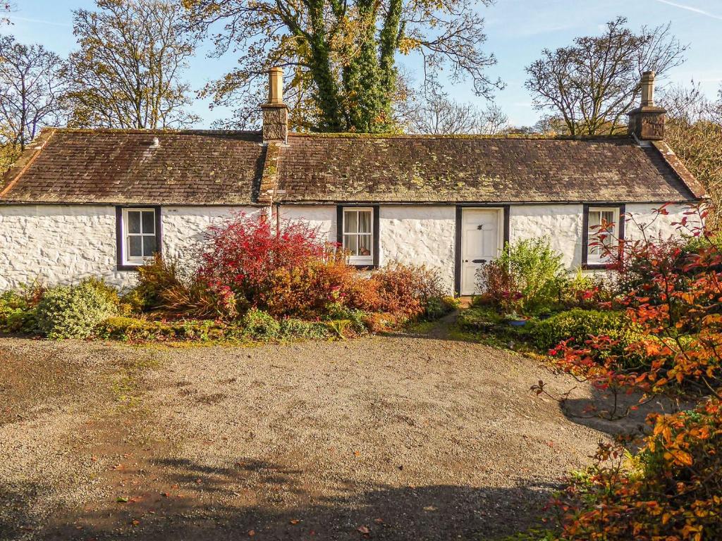 uma velha casa de pedra com uma entrada de cascalho em Bridge Cottage em Lockerbie