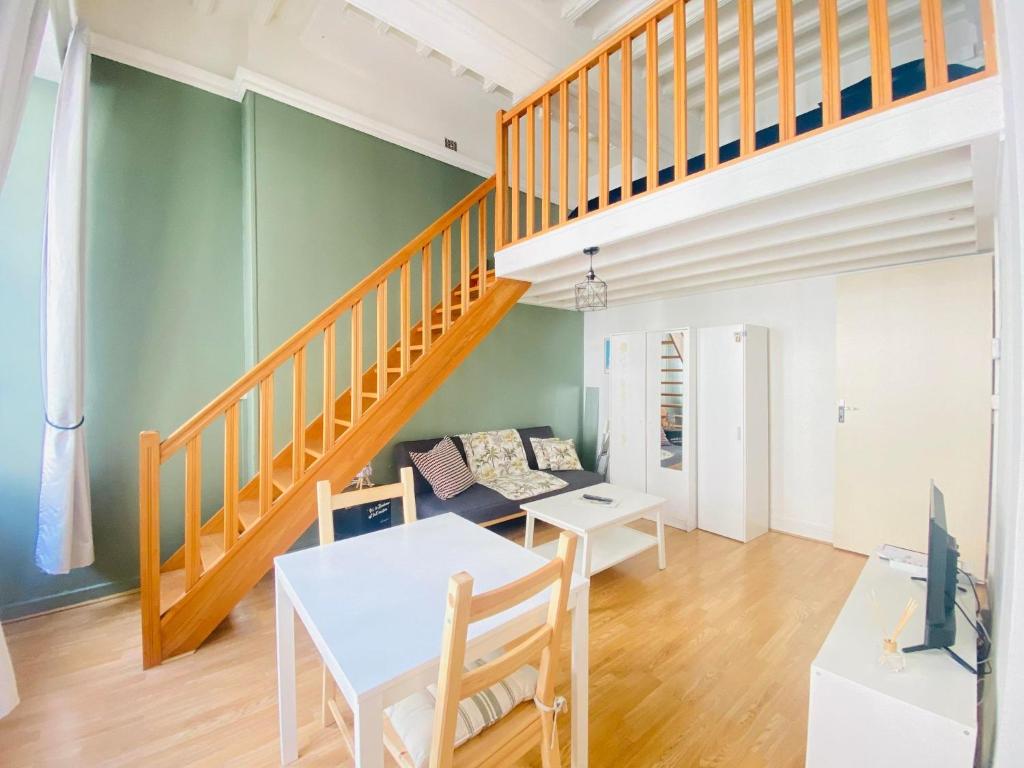 ein Wohnzimmer mit einem Tisch und einer Treppe in der Unterkunft Coeur de ville, appartement moderne avec mezzanine in Laon