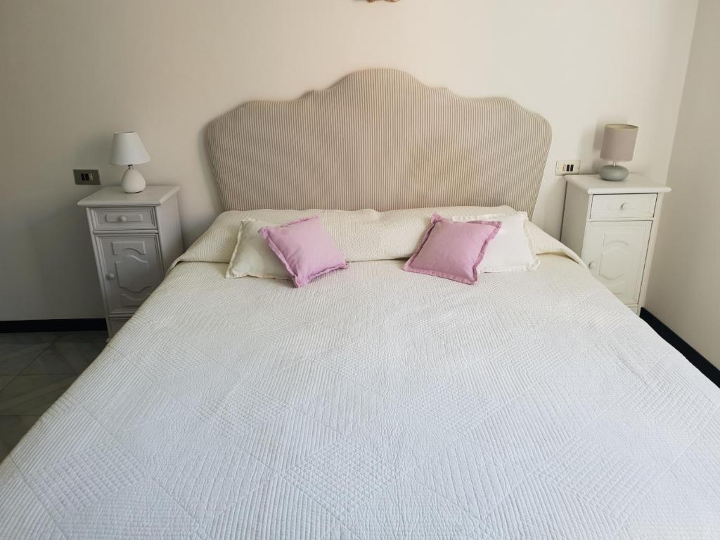a white bed with two purple pillows on it at Le stanze di Angelina in Foligno