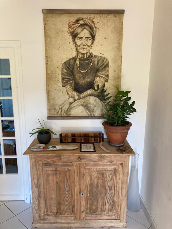 a painting of a woman sitting on a wooden cabinet at Amama Baita in Urrugne