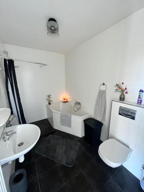 een badkamer met een bad, een toilet en een wastafel bij Parnassia in De Koog