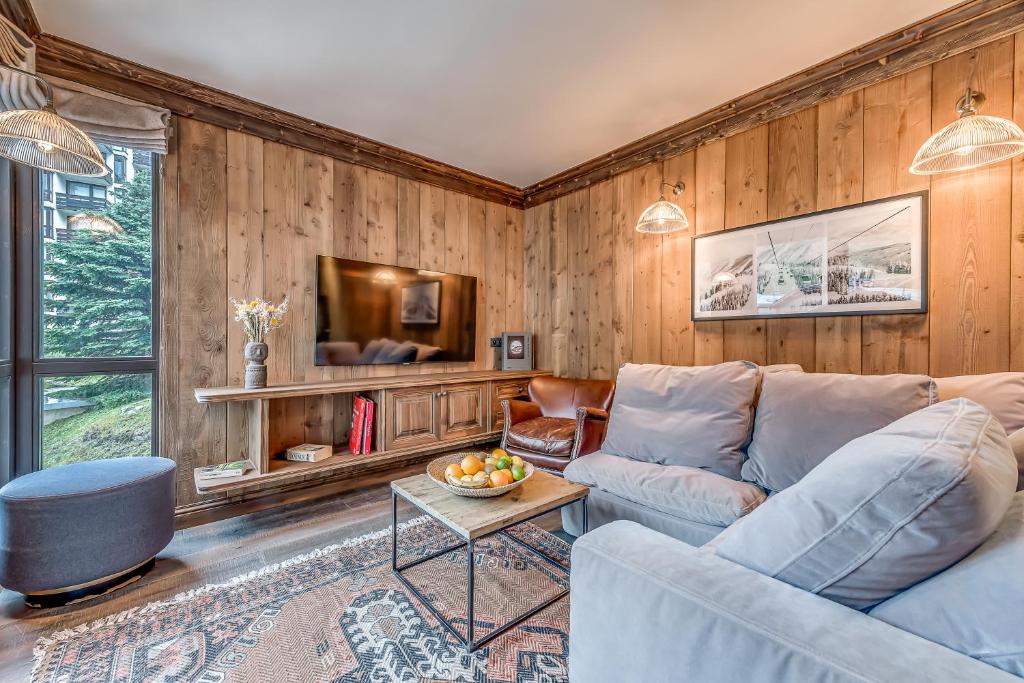 a living room with a couch and a tv at Hotel & Spa Le Val d'Isère in Val-d'Isère