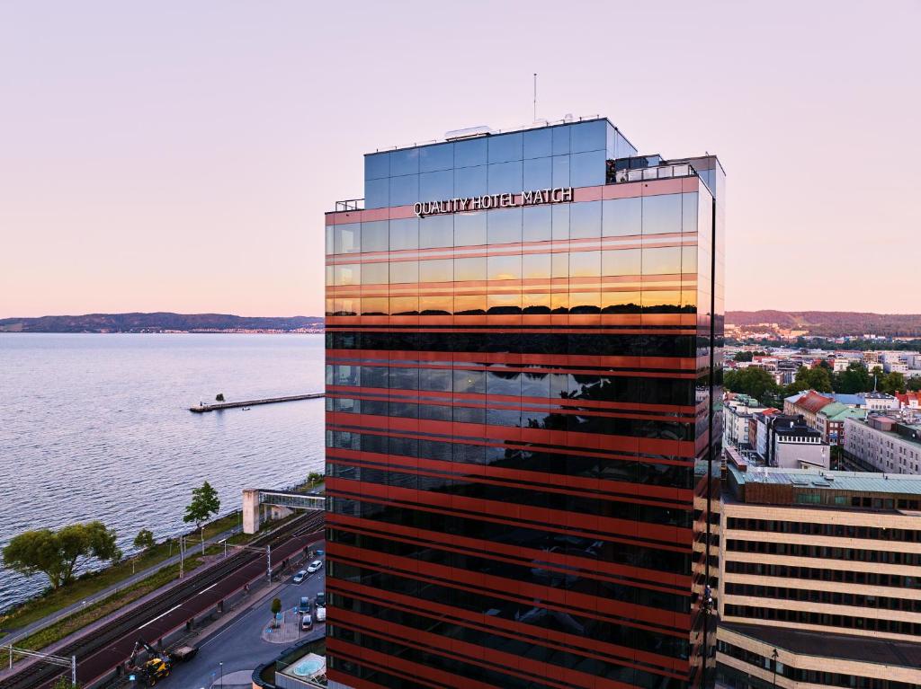 un grand bâtiment en verre reflétant l'eau dans l'établissement Quality Hotel Match, à Jönköping