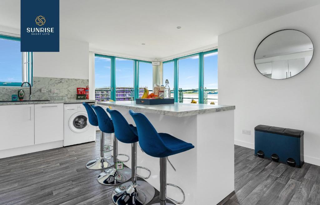 una cocina con encimera con taburetes de barra azul en THE PENTHOUSE, Spacious, Stunning Views, Foosball Table, 3 Large Rooms, Central Location, River Front, Tay Bridge, V&A, 2 mins to Train Station, City Centre, Lift Access, Parking, WiFi, Mid-Stay Rates Available by SUNRISE SHORT LETS en Dundee