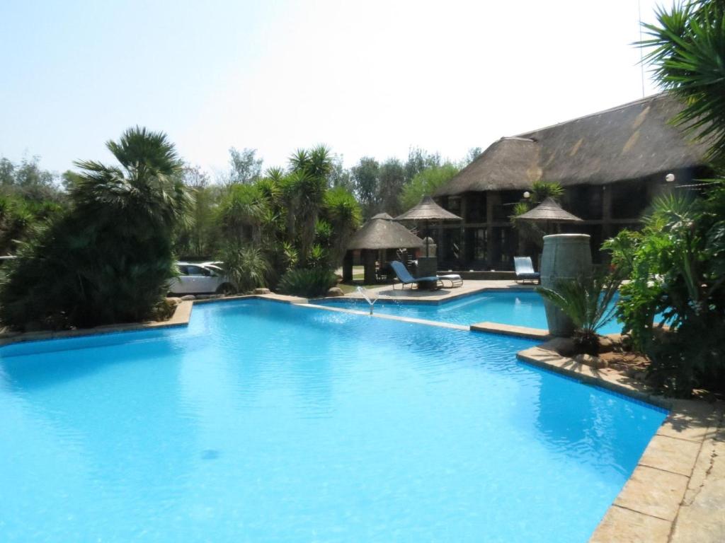 a large blue swimming pool next to a resort at Bushmans Rock in Pretoria