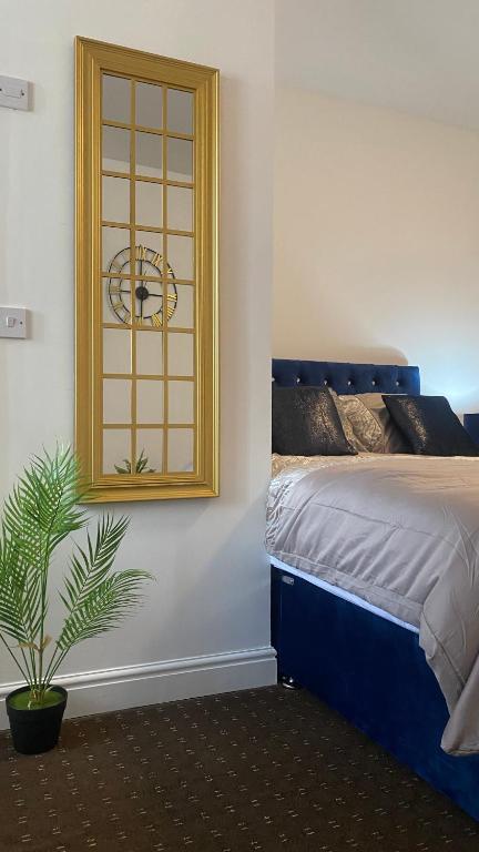 ein Schlafzimmer mit einer Uhr an der Wand und einer Pflanze in der Unterkunft Bv Comfy Studio At Deighton Huddersfield in Huddersfield