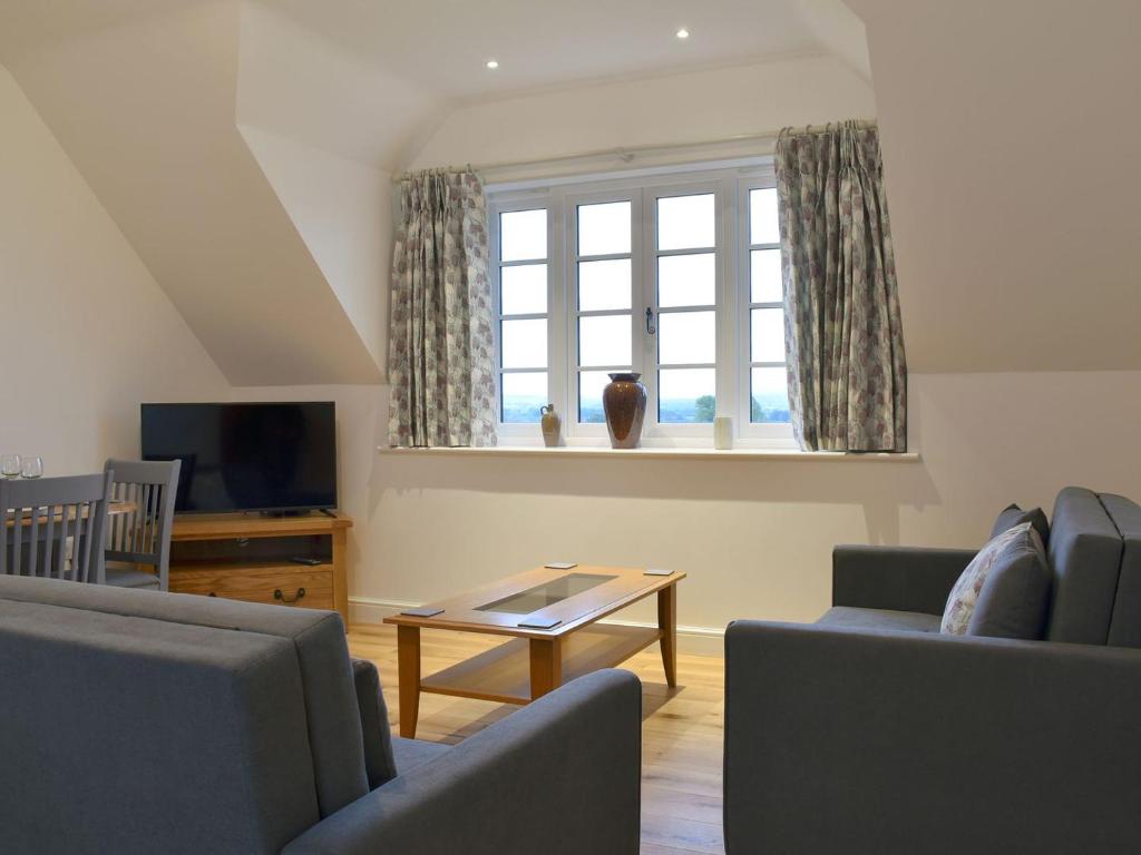 ein Wohnzimmer mit 2 Sofas, einem Tisch und einem Fenster in der Unterkunft The New Inn Barn-uk31813 in Marnhull