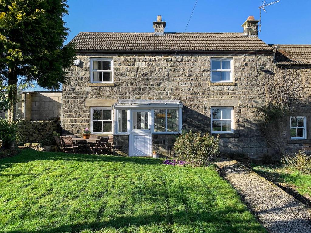a stone house with a lawn in front of it at Span Carr Cottage in Ashover