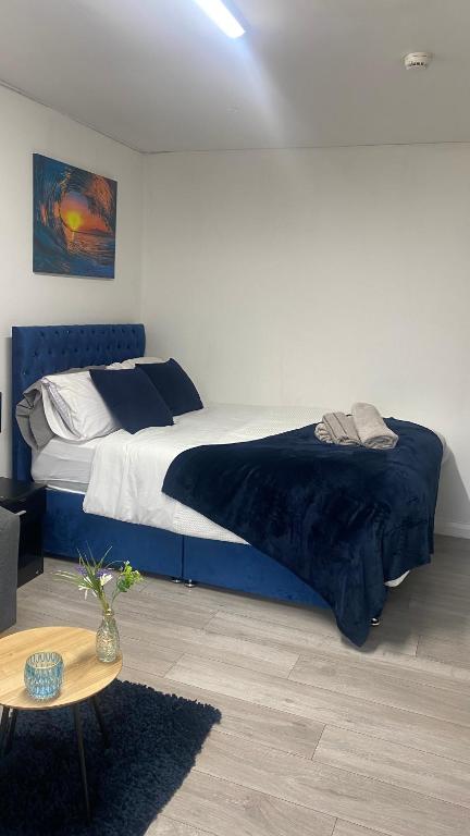 a bedroom with a bed with a blue blanket and a table at BV Royal Comfy Studio Seven Suite Queensgate Huddersfield in Huddersfield