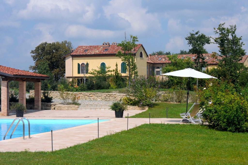 a house with a swimming pool and an umbrella at La Famulenta 17 in Grazzano Badoglio