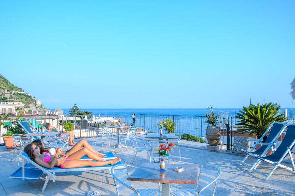 a woman laying in lawn chairs on a patio at Rooms B&B Albergo Riviera in Maiori