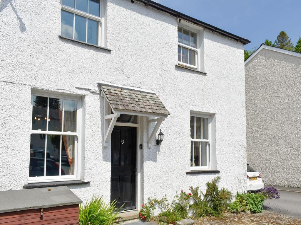 a white house with a black door and an awning at Primrose Cottage in Bowness-on-Windermere